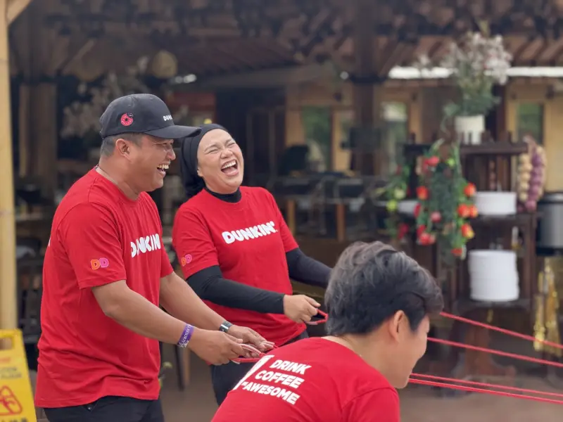Participants smiling while playing a coordinated team drum challenge